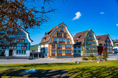 Lawn by building against blue sky