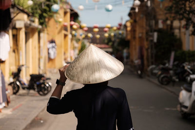  girl wearing vietnam hat or non la and sightseeing at heritage village in hoi an city in vietnam