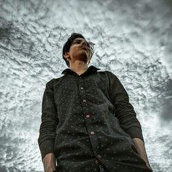 Young man looking away against wall