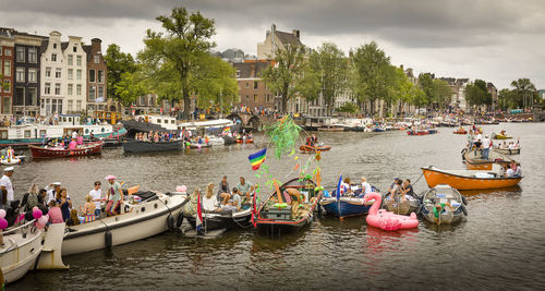 People on boats in river against sky