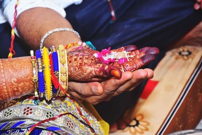 Midsection of couple holding hands in wedding ceremony