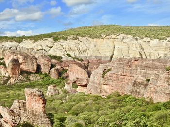 View of rock formations on landscape against cloudy sky