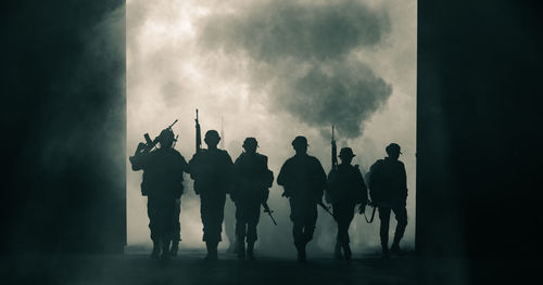 Silhouette army with guns walking during war