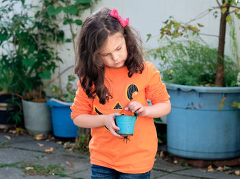 Little girl playing with bucket and plant seeds in the back yard