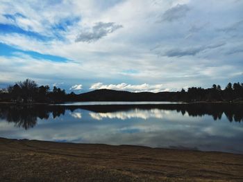 Scenic view of calm lake against cloudy sky