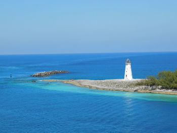 Lighthouse by sea against clear sky