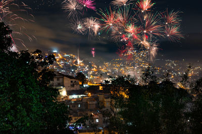 Firework display over illuminated cityscape at night