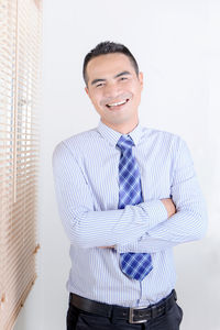 Portrait of businessman with arms crossed standing by window at office