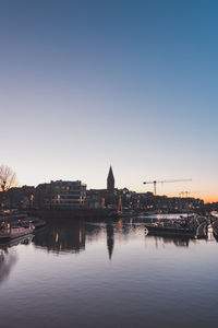 Buildings by river against clear sky