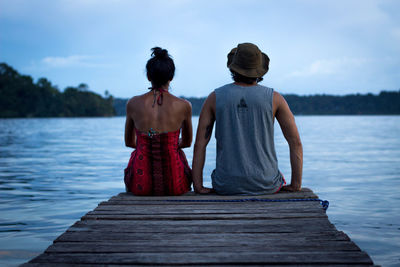 Rear view of men sitting on wooden pier