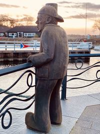 Statue on footpath in city against sky