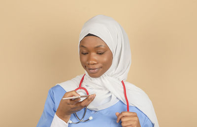 Young muslim nurse talking on mobile phone on color background person