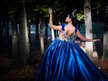 Rear view of woman in blue dress standing in forest