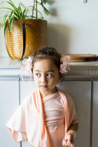 A little girl is standing in a beautiful dress with hair accessories. pretend play at home.