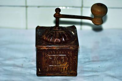 Close-up of old-fashioned coffee grinder against wall