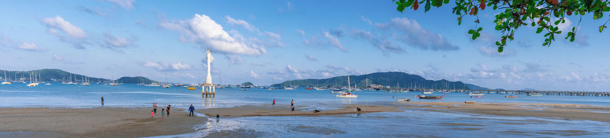 Panoramic view of people on beach against sky