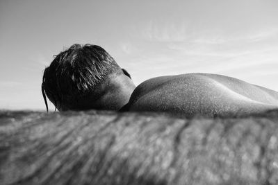 Surface level of man lying against sky