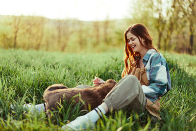 Side view of young woman sitting on field