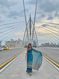 Portrait of woman in sari standing on bridge against sky