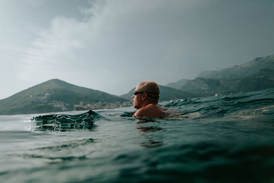 Woman swimming in sea against mountain