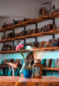 Close-up of flower vase on table against stack of books
