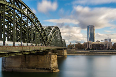 Bridge over river in city against sky