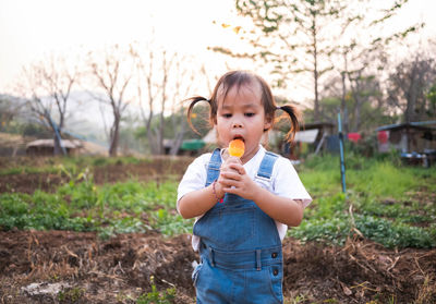 Girl eating flavored ice while standing on land