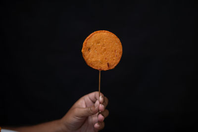 Person holding ice cream against black background