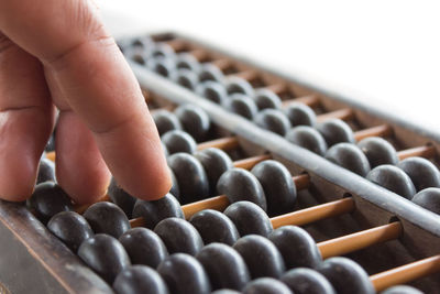 Cropped hand playing with abacus against white background