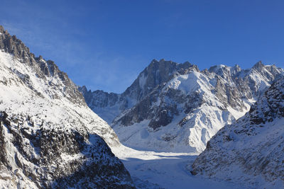 Scenic view of snowcapped mountains against blue sky