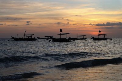 Silhouette boats in sea against sky during sunset