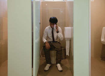 Man using mobile phone in toilet