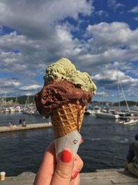 Close-up of woman holding ice cream cone against sky