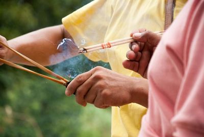 Midsection of people holding incense sticks