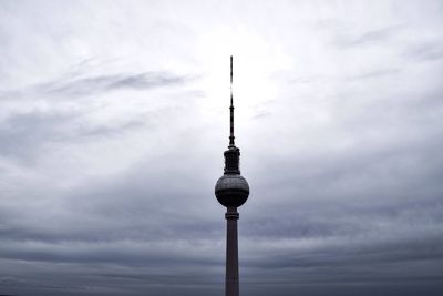 Low angle view of communications tower against cloudy sky