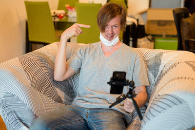 Portrait of man photographing while sitting on sofa at home