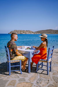 Couple sitting at restaurant against sea