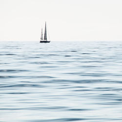 Sailboat sailing on sea against clear sky