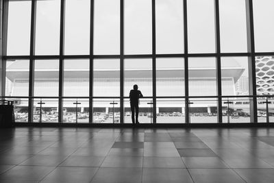 Man at airport against sky seen through window