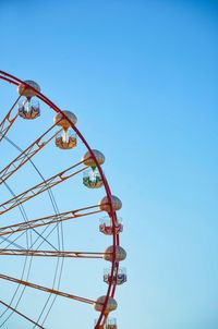 Low angle view of ferris wheel against clear blue sky