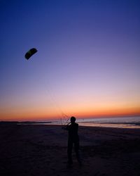 Silhouette man on beach against sky during sunset