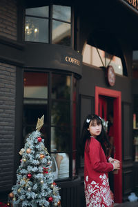 Portrait of woman standing by christmas tree