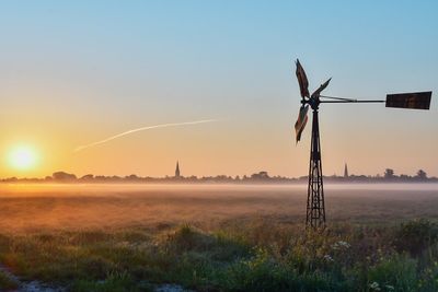 Windmills on field against sky during sunset