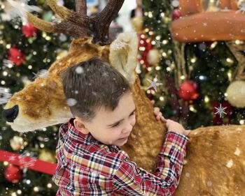 Cute boy hugging deer during winter