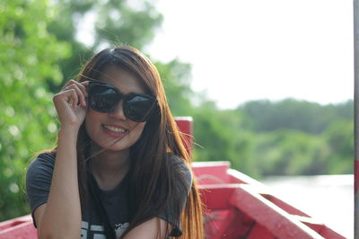 Portrait of woman wearing sunglasses while sitting on boat in lake