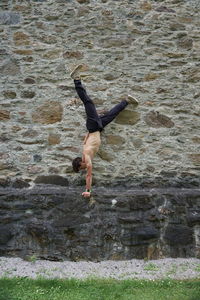 Young man exercising by stone wall