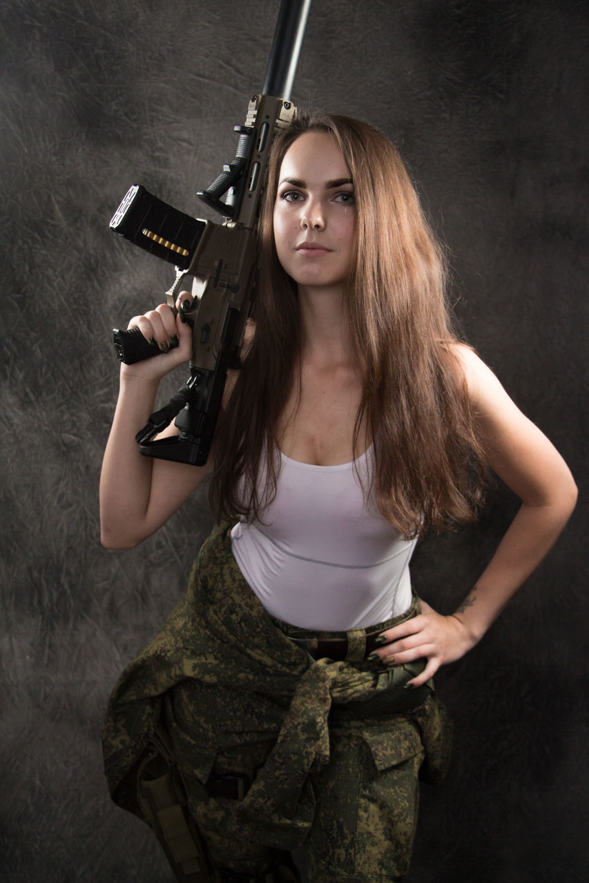 PORTRAIT OF YOUNG WOMAN STANDING AGAINST WALL