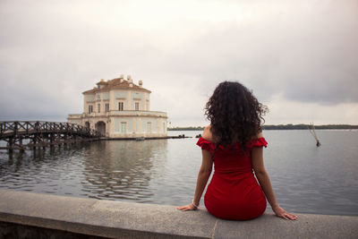 Rear view of woman looking at view of river against sky