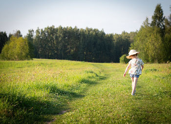Rear view of baby girl walking on grassy field