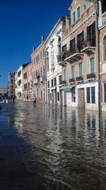 Canal amidst buildings against clear blue sky